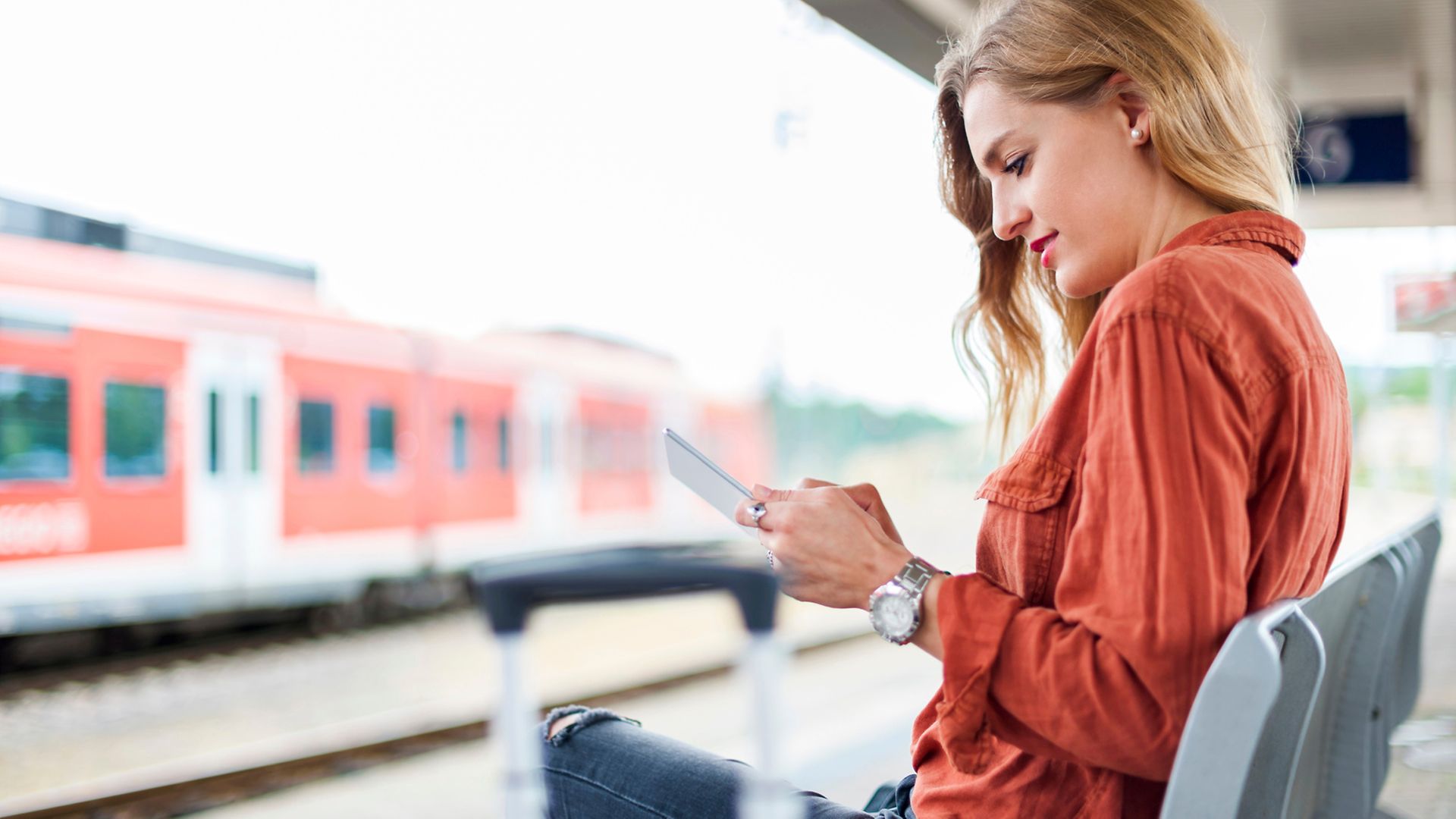 Personen mit Smartphone am Bahnsteig